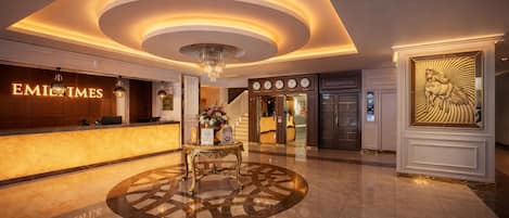 Una hall d'hotel dal design moderno, con una reception, un lampadario e un elemento decorativo a parete.