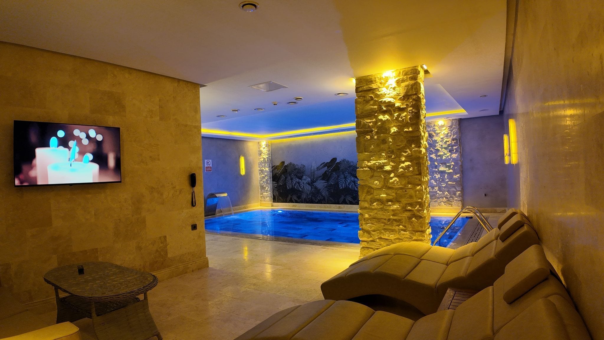 A spa area with a pool, massage chairs, and a television screen.