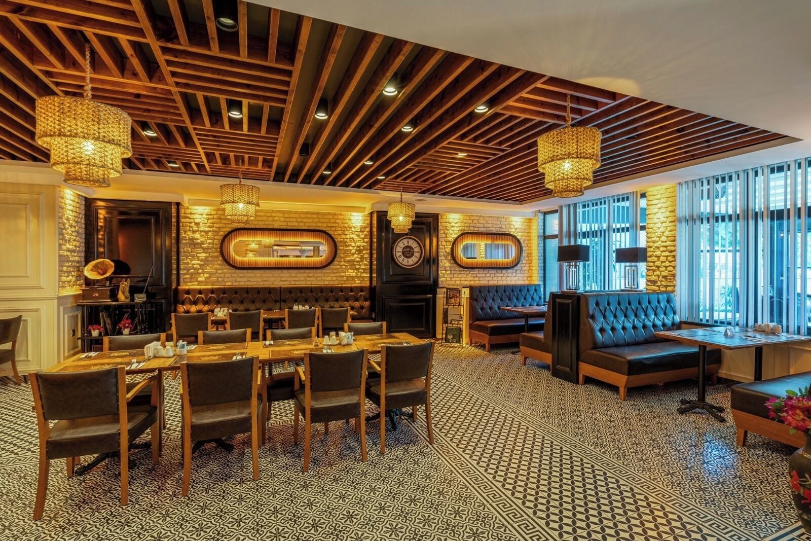 A restaurant with a high ceiling, exposed wooden beams, and patterned flooring.