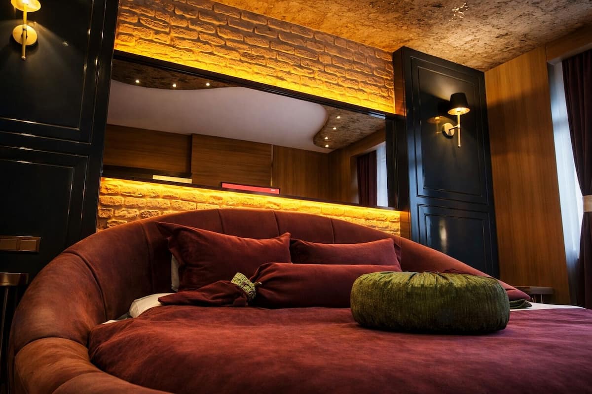 A modern bedroom with a curved bed, a brick accent wall, and built-in lighting.