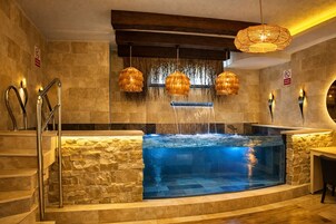 Un área de spa con pared de piedra, un jacuzzi y una escalera de madera.