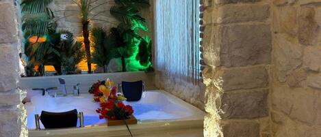 Un área de spa con una bañera, asientos y una decoración vegetal.