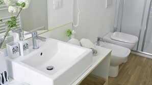 A modern bathroom with a large white sink, a handheld showerhead, a toilet, and a mirror. - Altamarea (La Spezia)