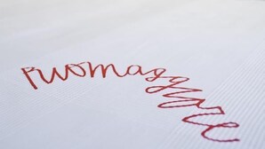 A bed with a white sheet and a red embroidered name. - Altamarea (La Spezia)