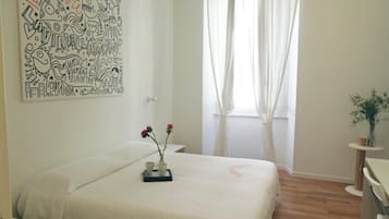 A bedroom with a bed, a bedside table, a window with curtains, and a wall with doodle art.