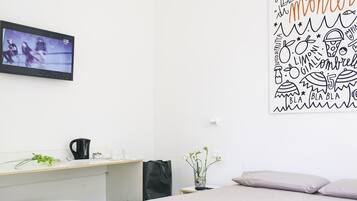A bedroom with a bed, a desk, and a TV.