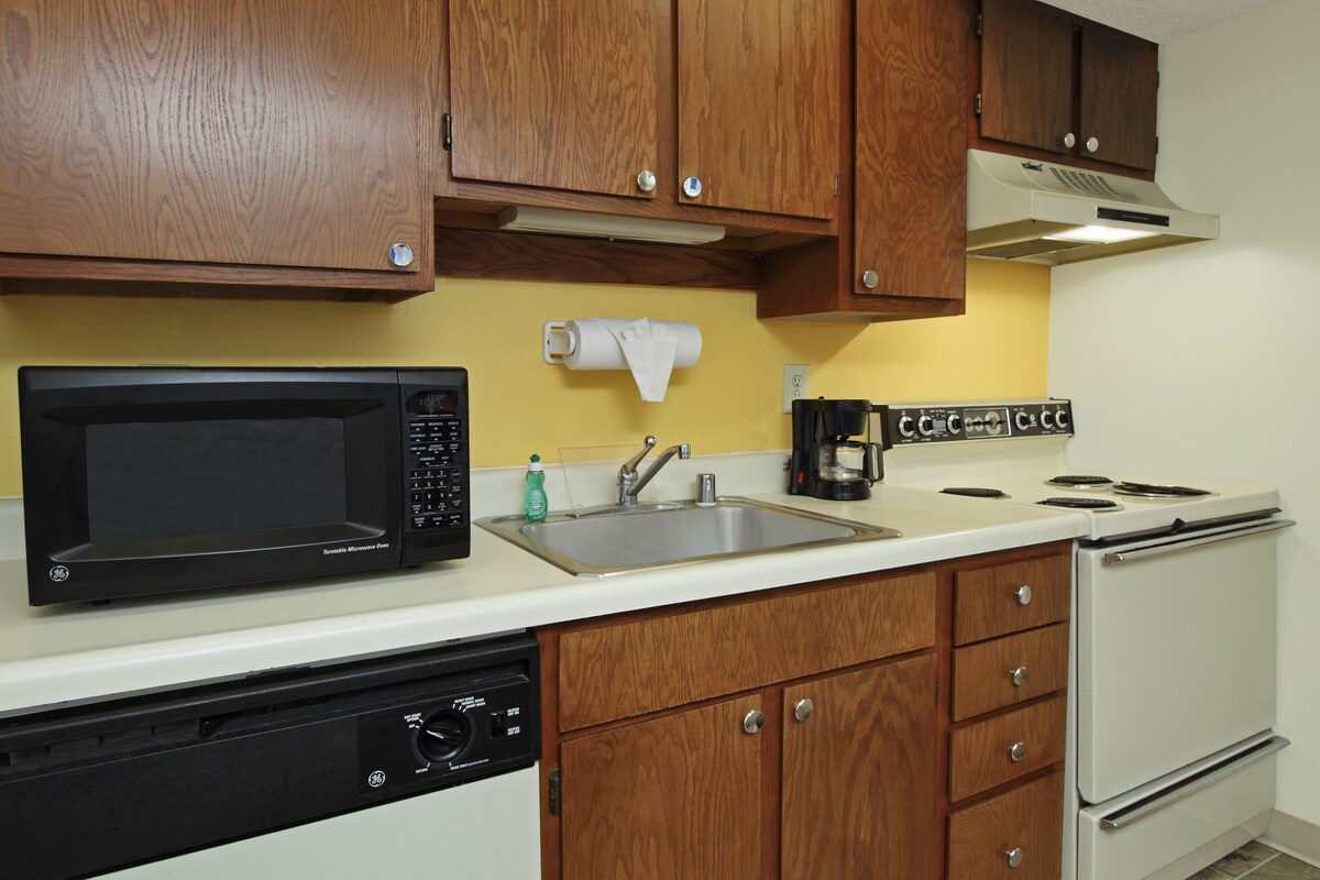 A kitchen with wooden cabinets, a microwave, a sink, a coffee maker, and a dishwasher.