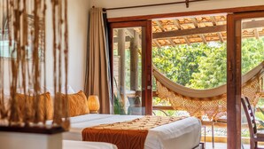 Un dormitorio con dos camas, una hamaca y vistas al verdor exterior.