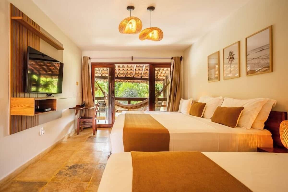 A hotel room with a TV, two beds, a hammock, and a balcony with a view.