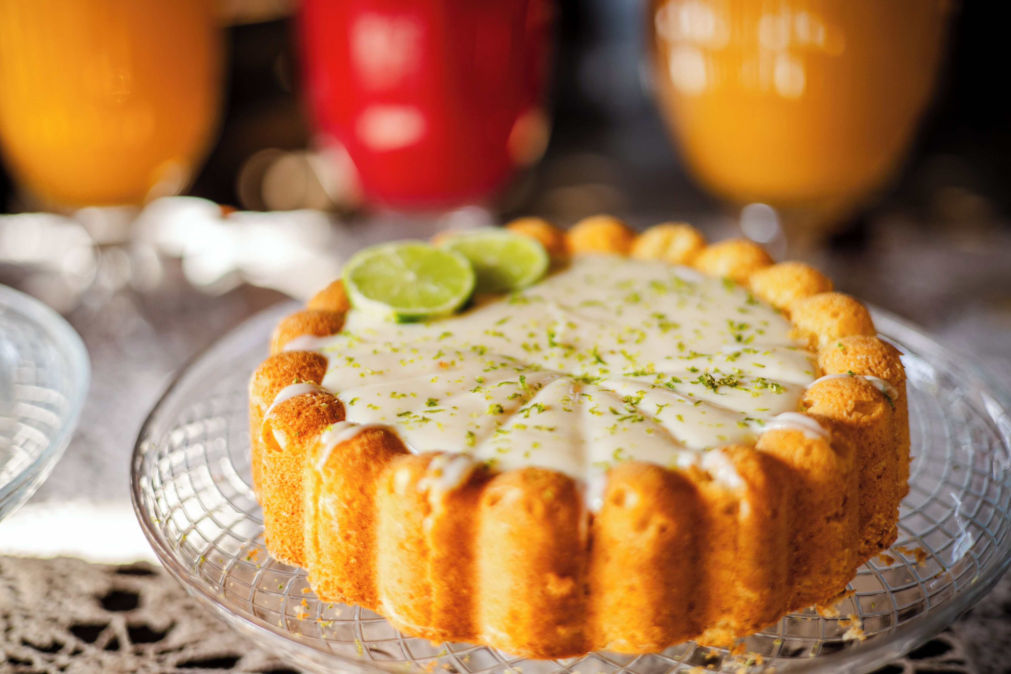 Un postre con cobertura blanca y rodajas de limón sobre un plato de vidrio transparente.