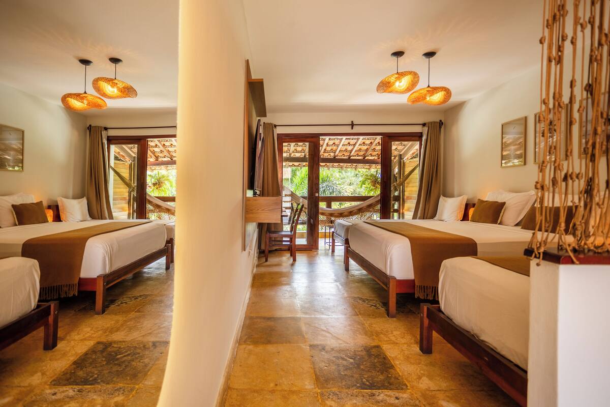 A hotel room with two beds, a large window, and a view of the outdoors.