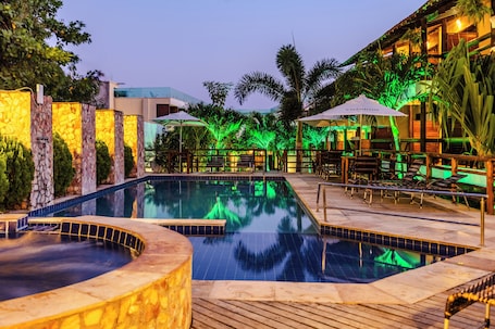 Una piscina al aire libre, sombrillas, sillones reclinables de piscina