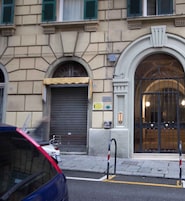 Un edificio con una puerta tapiada, una amplia entrada en arco y una pequeña señal sobre la puerta.