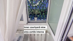Vista desde una ventana a un patio interior con flores blancas y follaje verde.