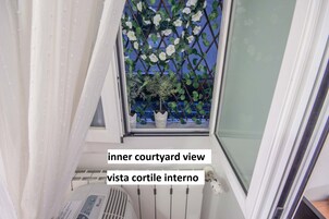 Vista desde una ventana a un patio interior con flores blancas y follaje verde.