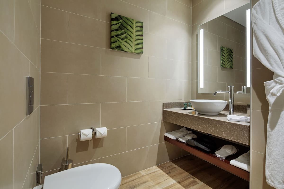 A modern bathroom with a white sink, mirror, and toilet.