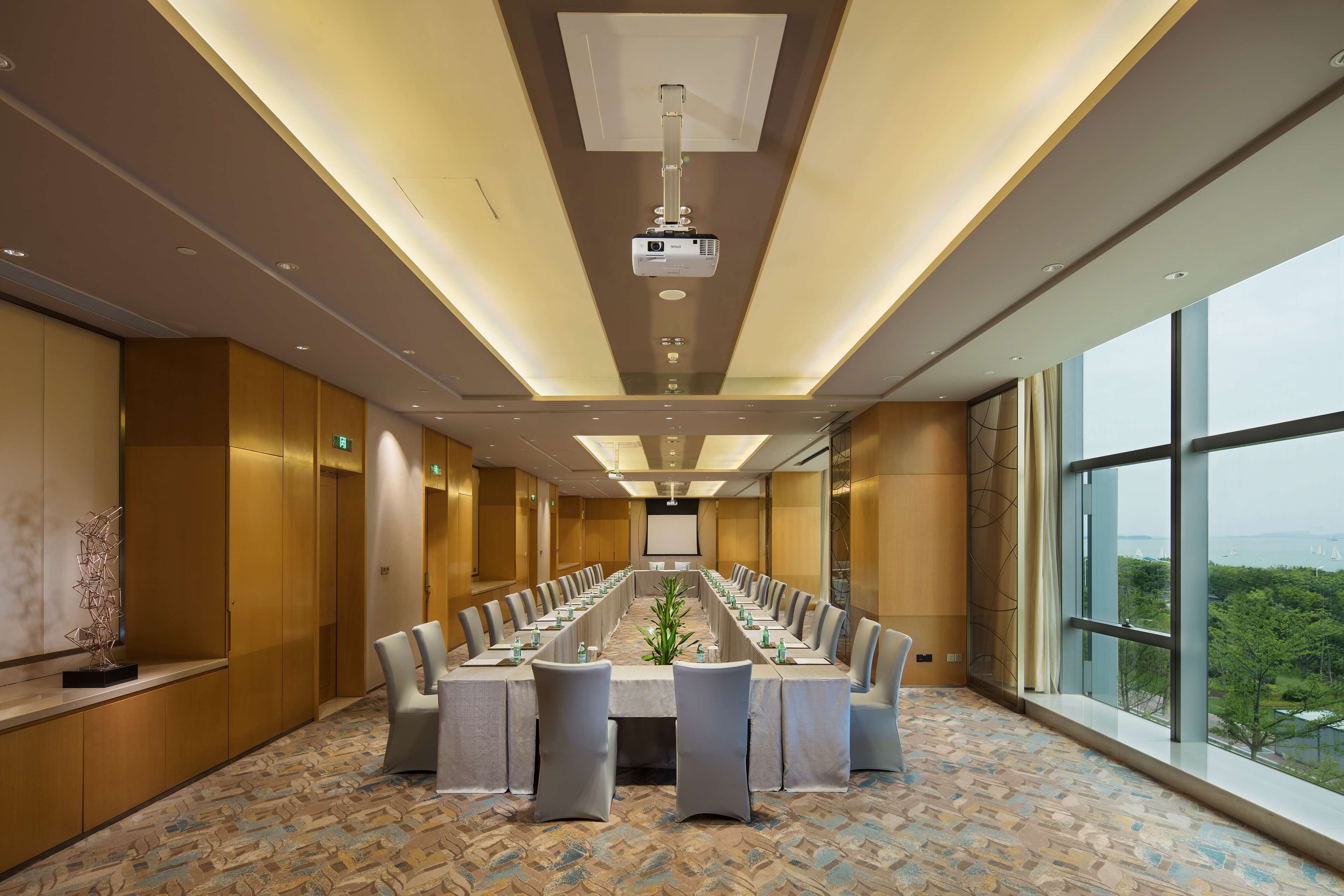 A conference room with a long table, chairs, and a projector screen.