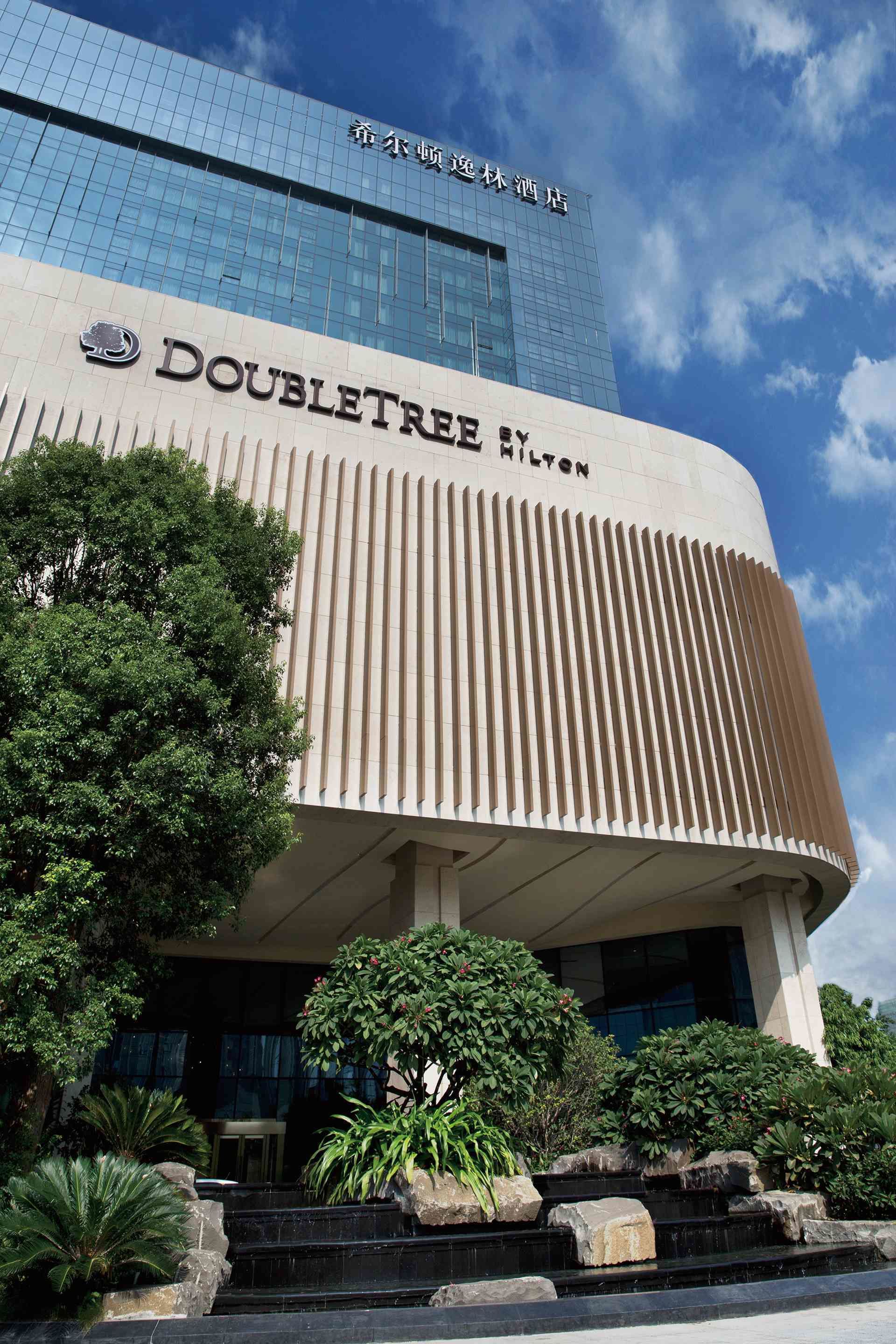 A hotel with a modern facade, featuring the name 'DOUBLETREE by Hilton' prominently displayed.