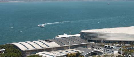 A modern building with a curved roof, adjacent to a body of water with a boat.