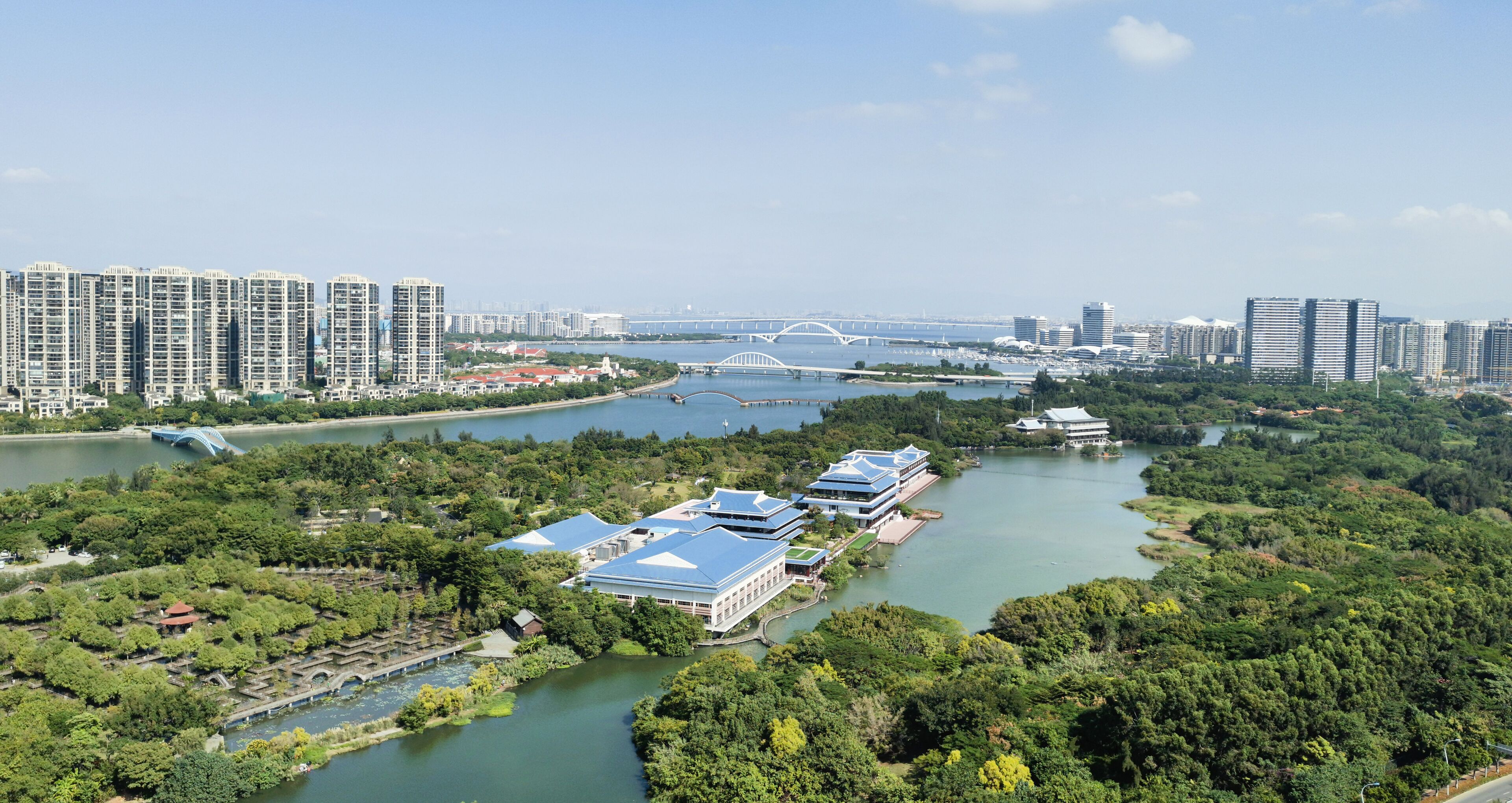 A riverside view of a city with high-rise buildings, a bridge, and traditional architecture.