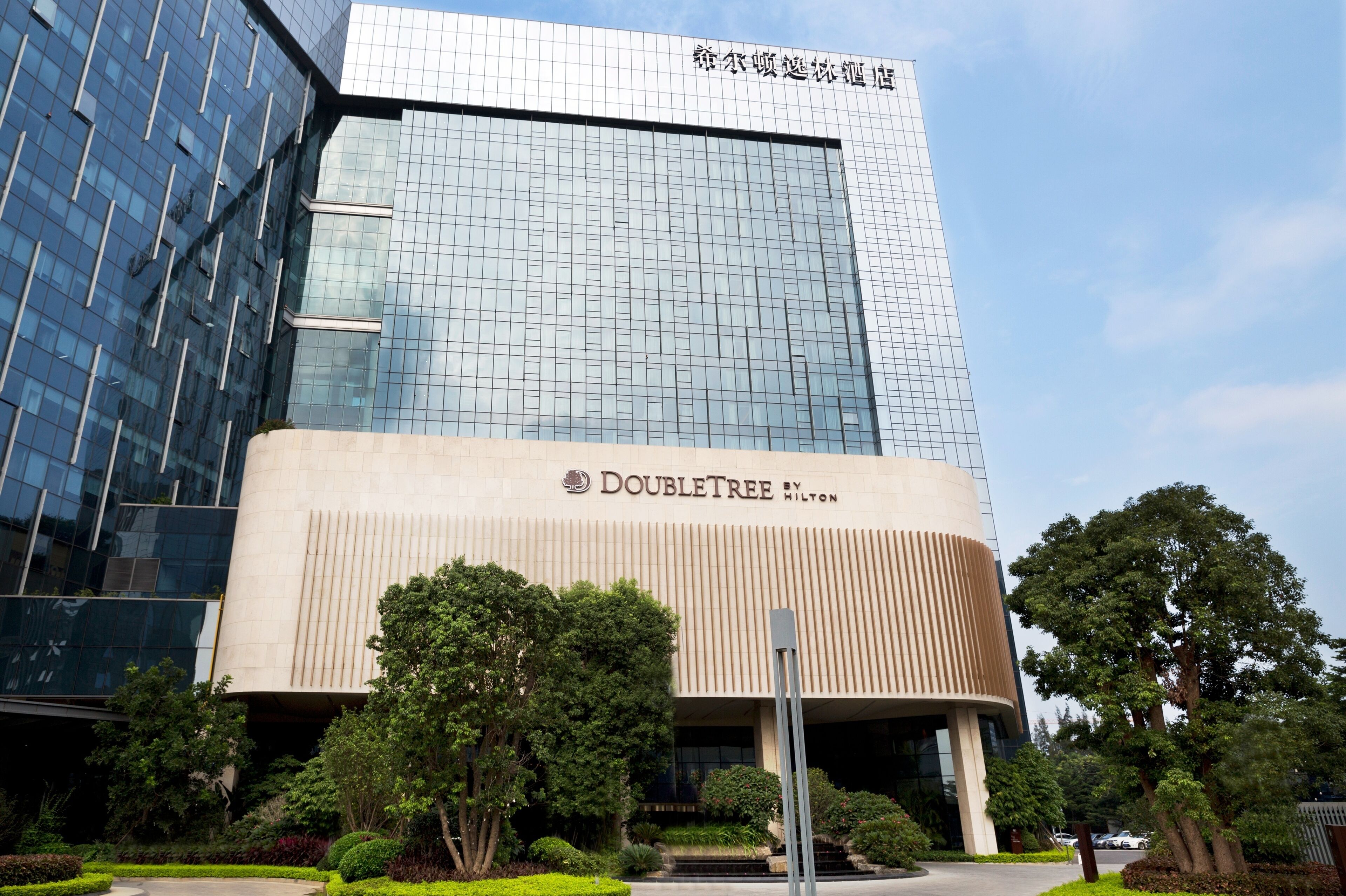 Een modern hotelgebouw met een glazen gevel en een opvallend DoubleTree Hilton bord.