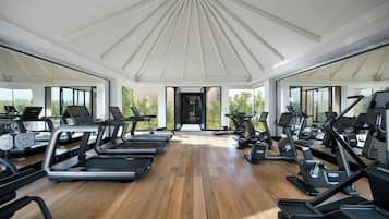 A gym with treadmills, stationary bikes, and elliptical machines arranged in rows.