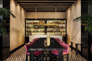 A bar area with a long table, multiple shelves of bottles, and red chairs. - Mandarin Oriental, Marrakech (Marrakech)