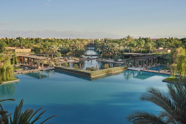 A resort with multiple swimming pools, palm trees, and a mountainous backdrop. - Mandarin Oriental, Marrakech (Marrakech)
