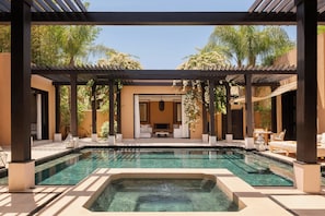 A pool area with a hot tub, outdoor seating, and a covered patio.