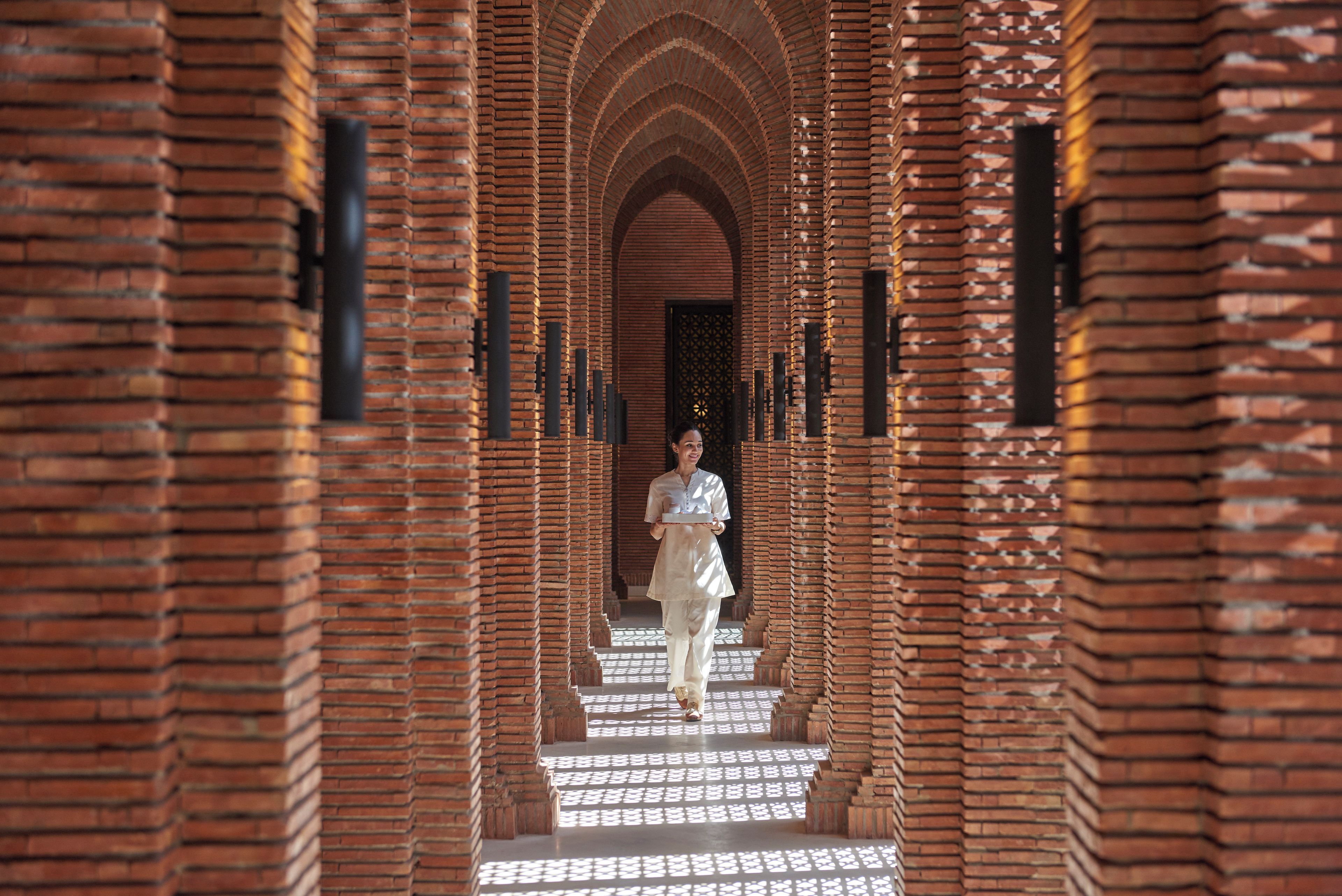 A corridor with brick walls and a person walking down the stairs.