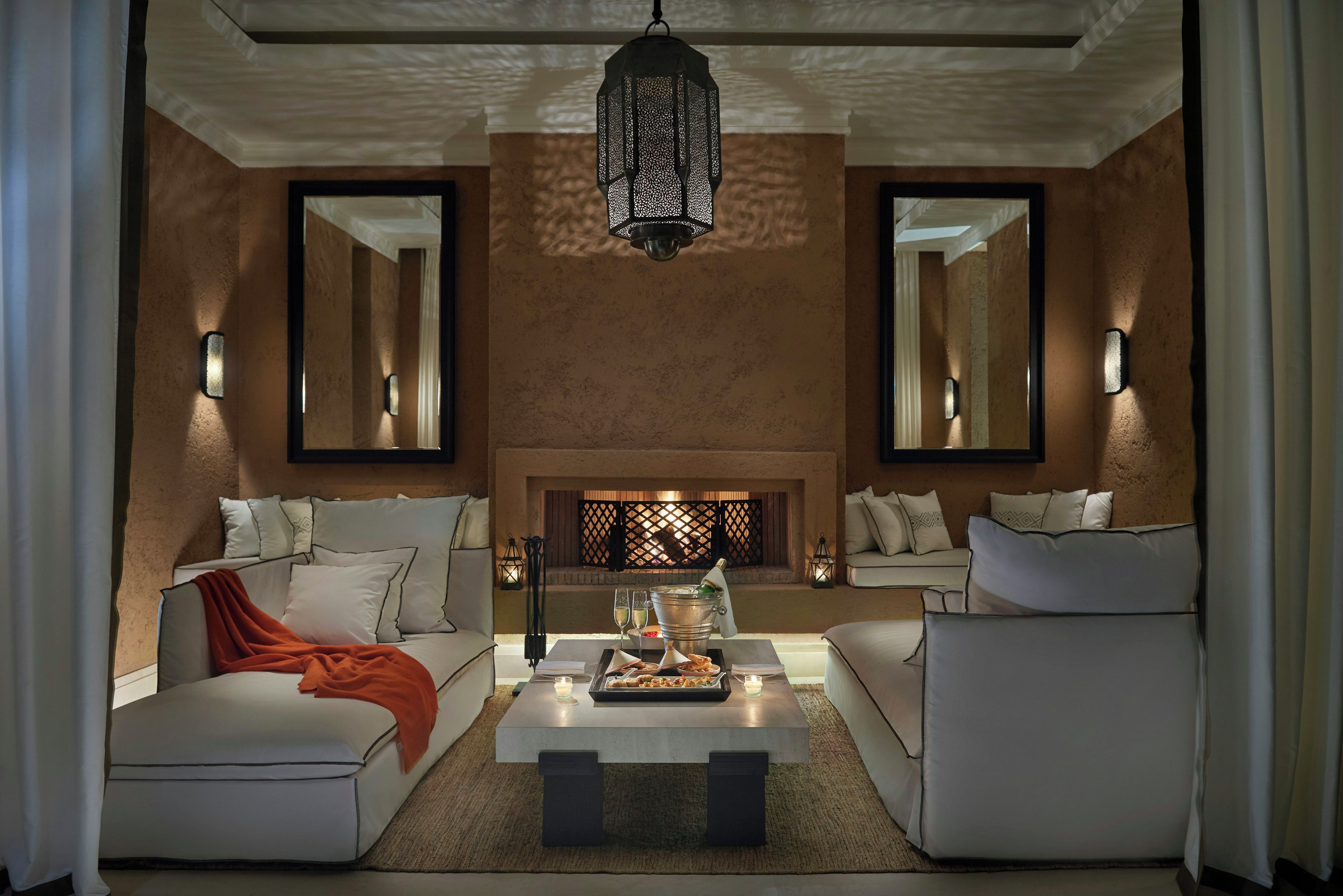 A modern living room with a fireplace, two sofas, a coffee table, and wall-mounted sconces.
