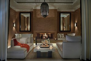A modern living room with a fireplace, two sofas, a coffee table, and wall-mounted sconces. - Mandarin Oriental, Marrakech (Marrakech)
