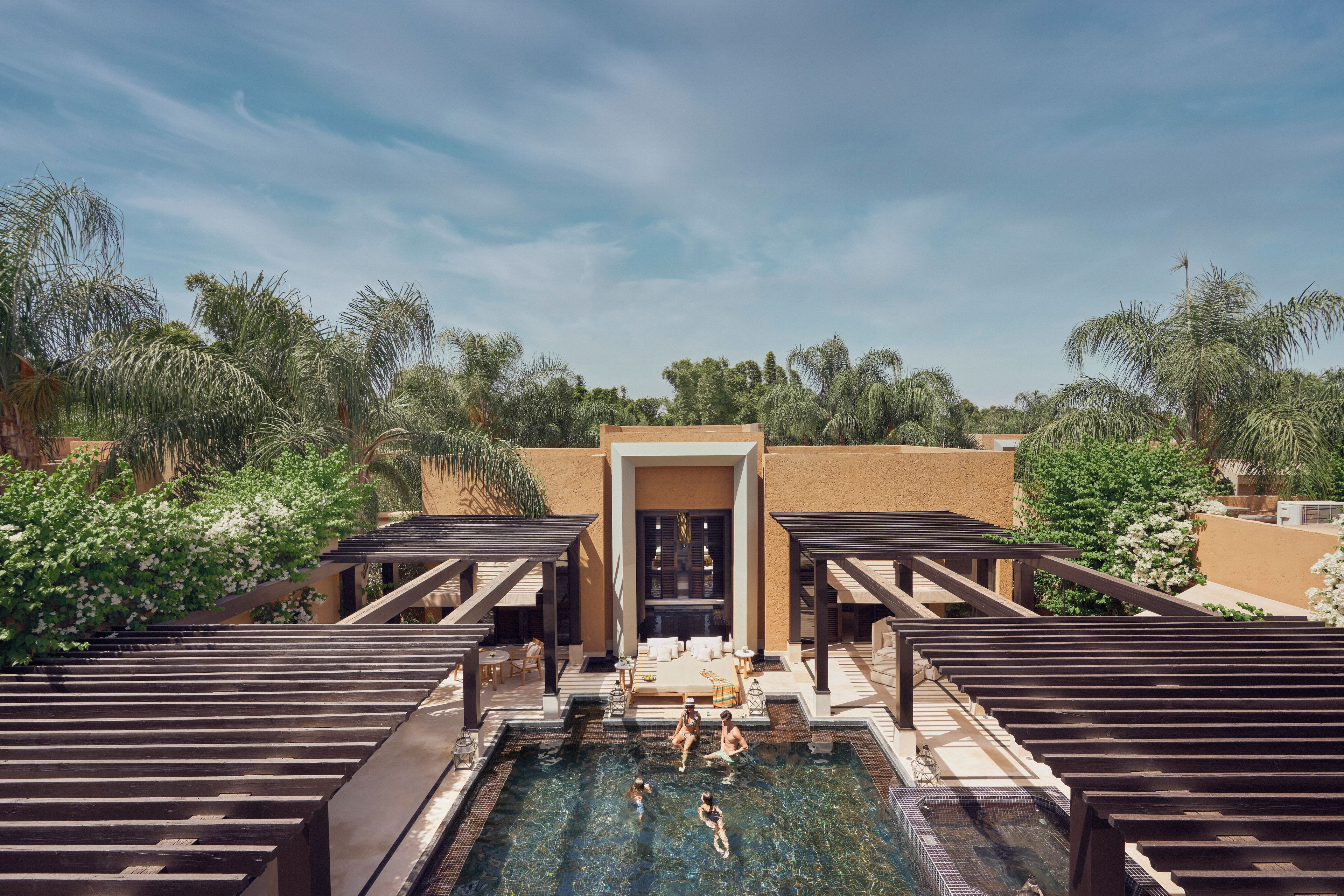 A pool area with a clear view of the water, surrounded by wooden deck seating and a covered entrance.