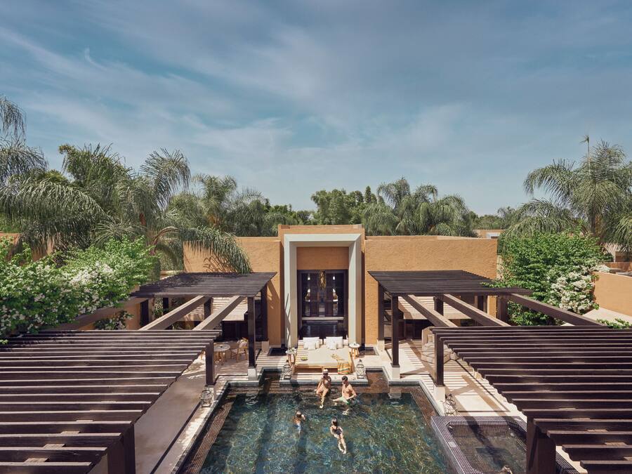 A pool area with a clear view of the water, surrounded by wooden deck seating and a covered entrance.