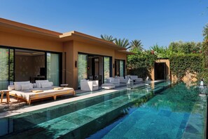 A modern poolside area with a clear pool, white outdoor furniture, and a large glass door entrance. - Mandarin Oriental, Marrakech (Marrakech)