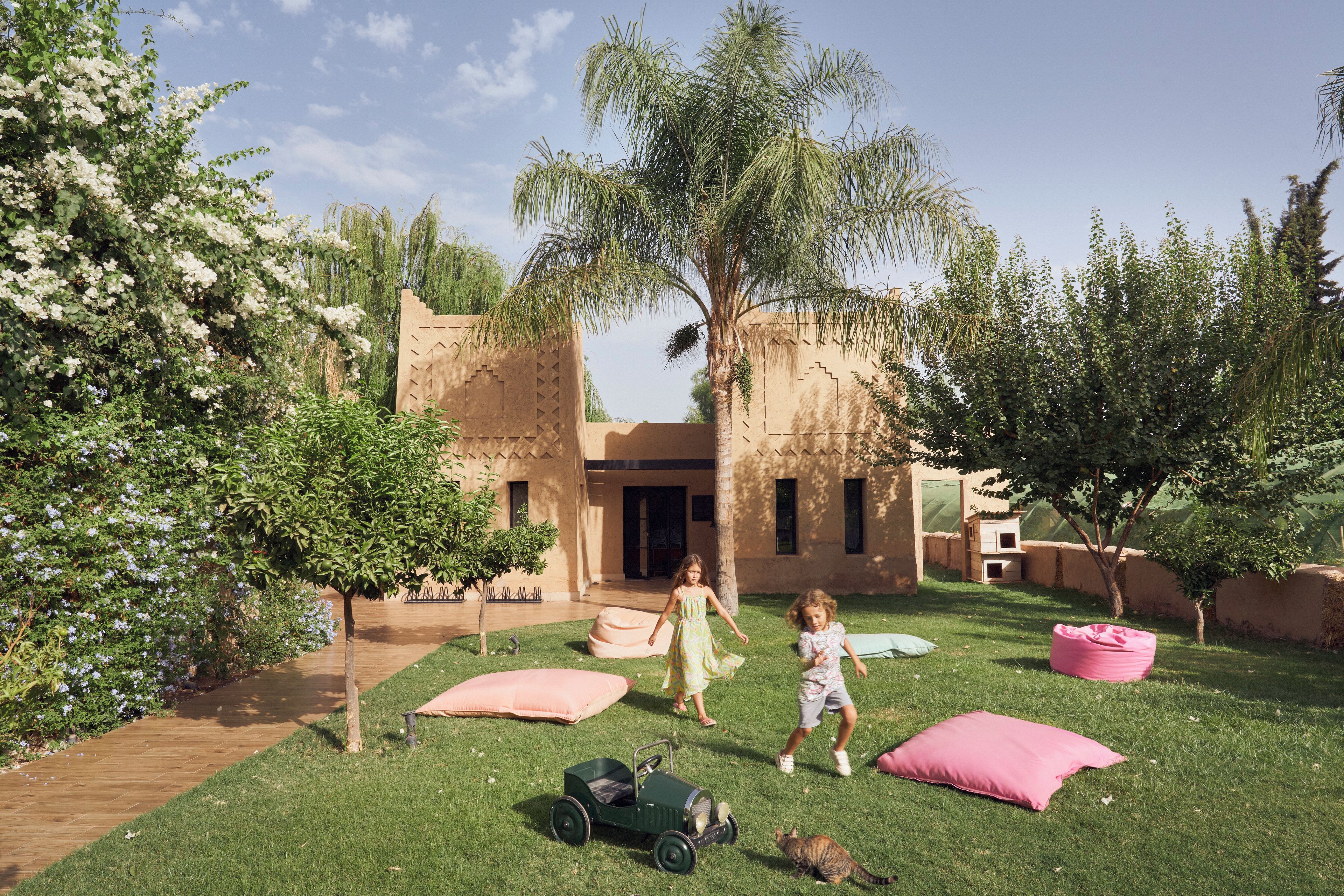 A courtyard with a lawn, a small play area, and a building with a unique architectural style.