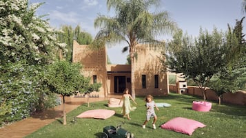 A courtyard with a lawn, a small play area, and a building with a unique architectural style.