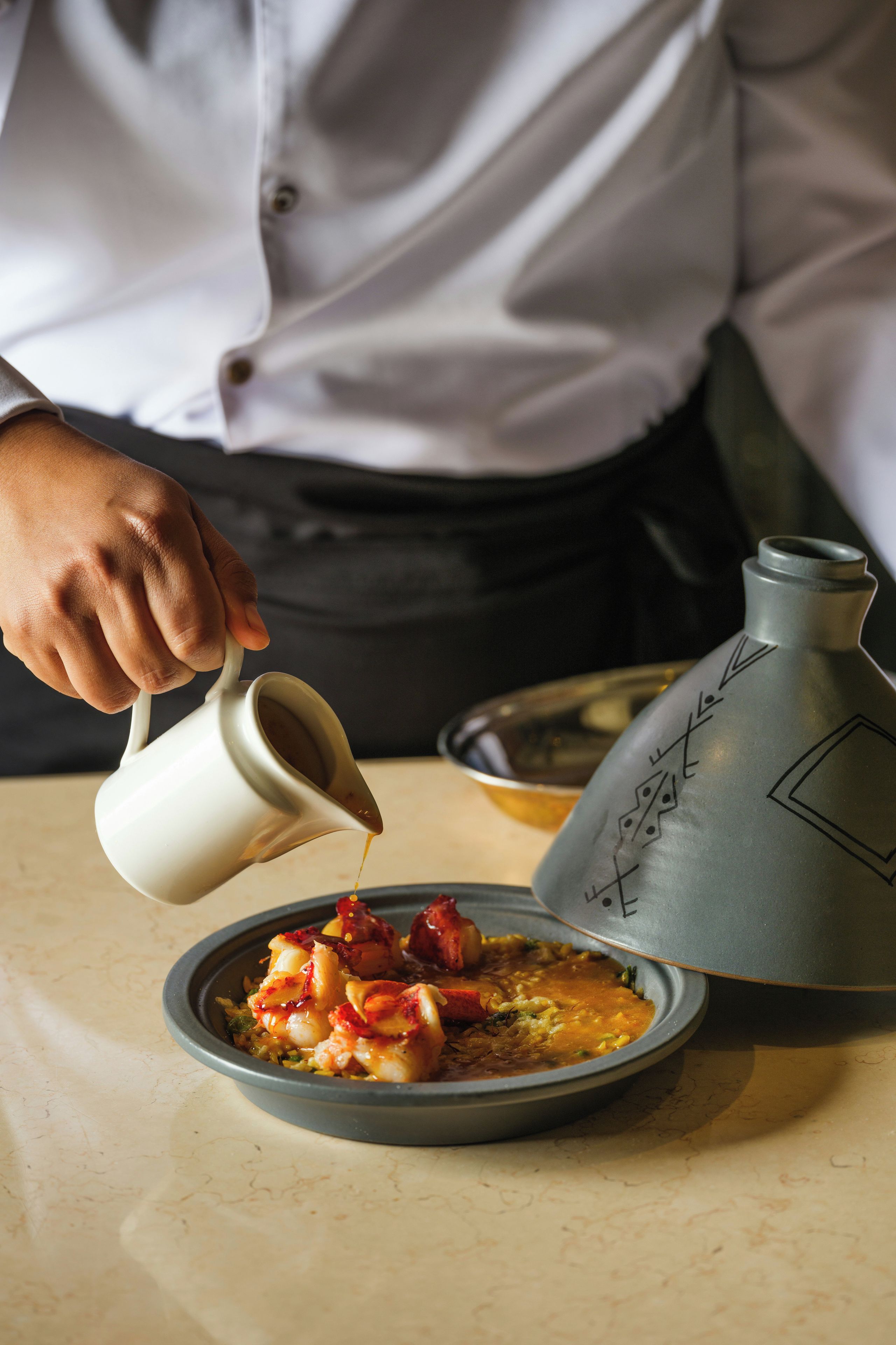 A person pouring a liquid from a jug into a bowl of food.
