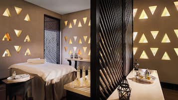 A modern room with a bed, a table with tea and glasses, and a wall with triangular light fixtures.