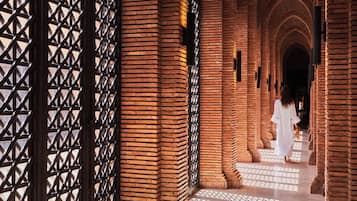 Un pasillo con paredes de ladrillo y una estructura de celosía a un lado.