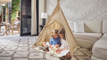 A cozy indoor setting with a teepee tent, a sofa, and a patterned rug.