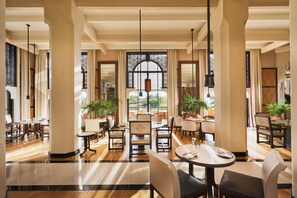 A spacious hotel lobby with multiple dining areas, large windows, and potted plants. - Mandarin Oriental, Marrakech (Marrakech)