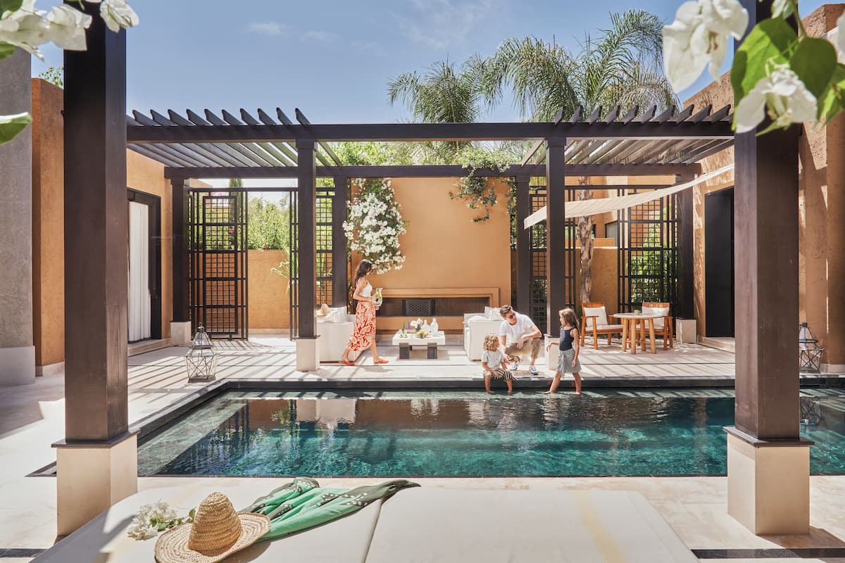 Área de piscina com pergolado, assentos e vista para o exterior.