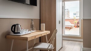 A hotel room with a wooden desk, a chair, a television mounted on the wall, and a view of the outside balcony. - BYPILLOW House (Barcelona)
