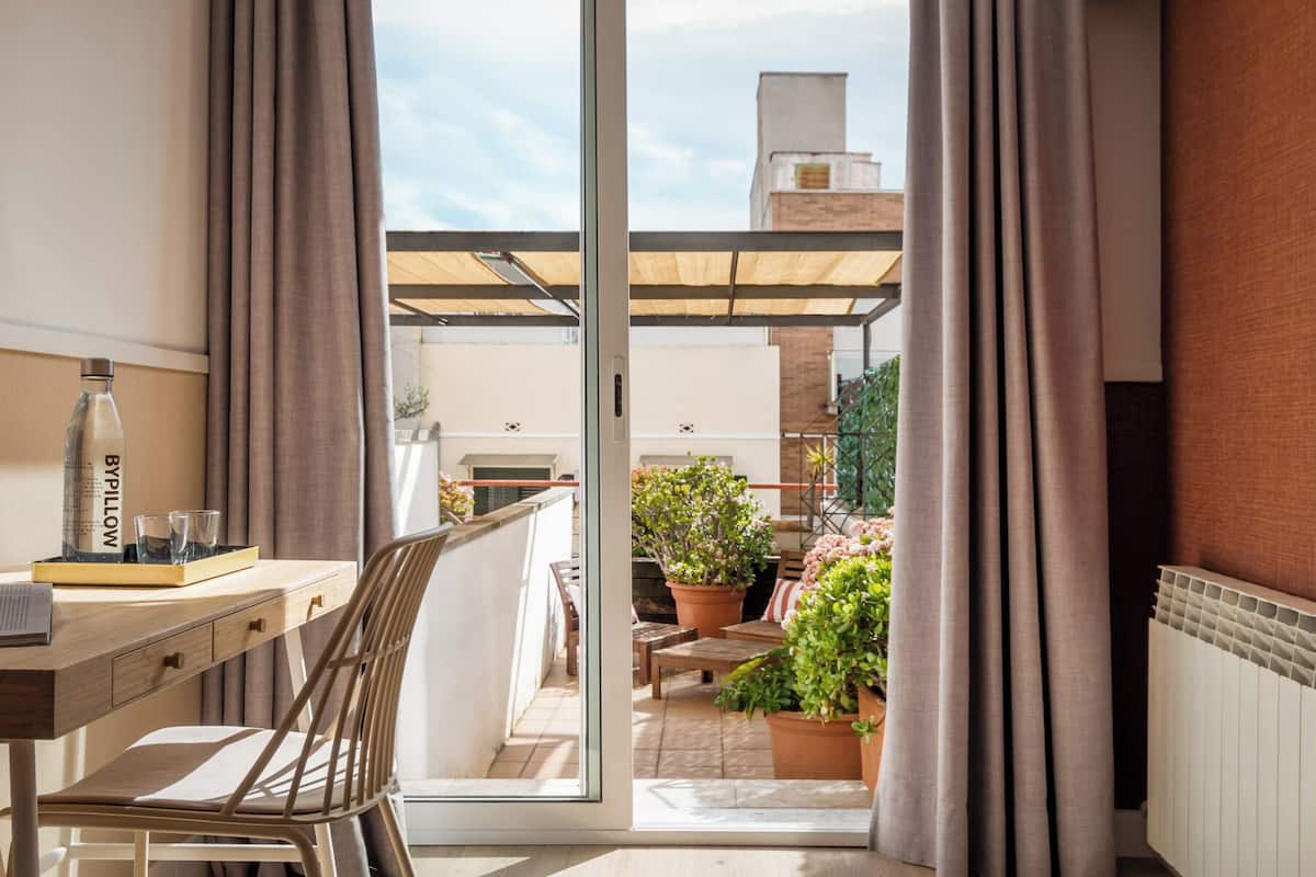 A balcony with a wooden table, chairs, and a bottle of BYPILLOW water.