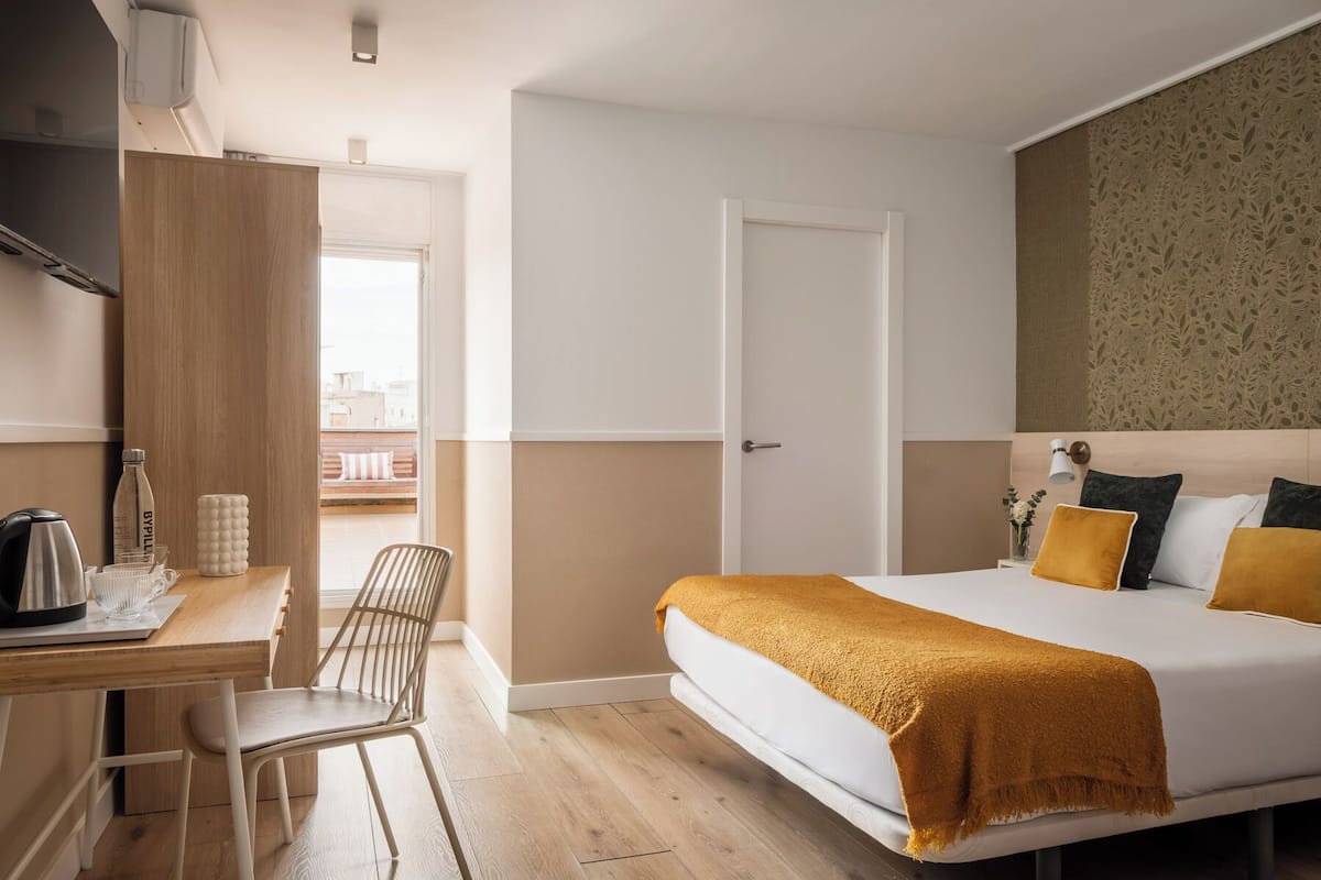 A modern hotel room with a bed, a desk, and a chair.
