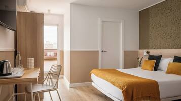 Ett modernt hotellrum med en säng, ett skrivbord och en stol.