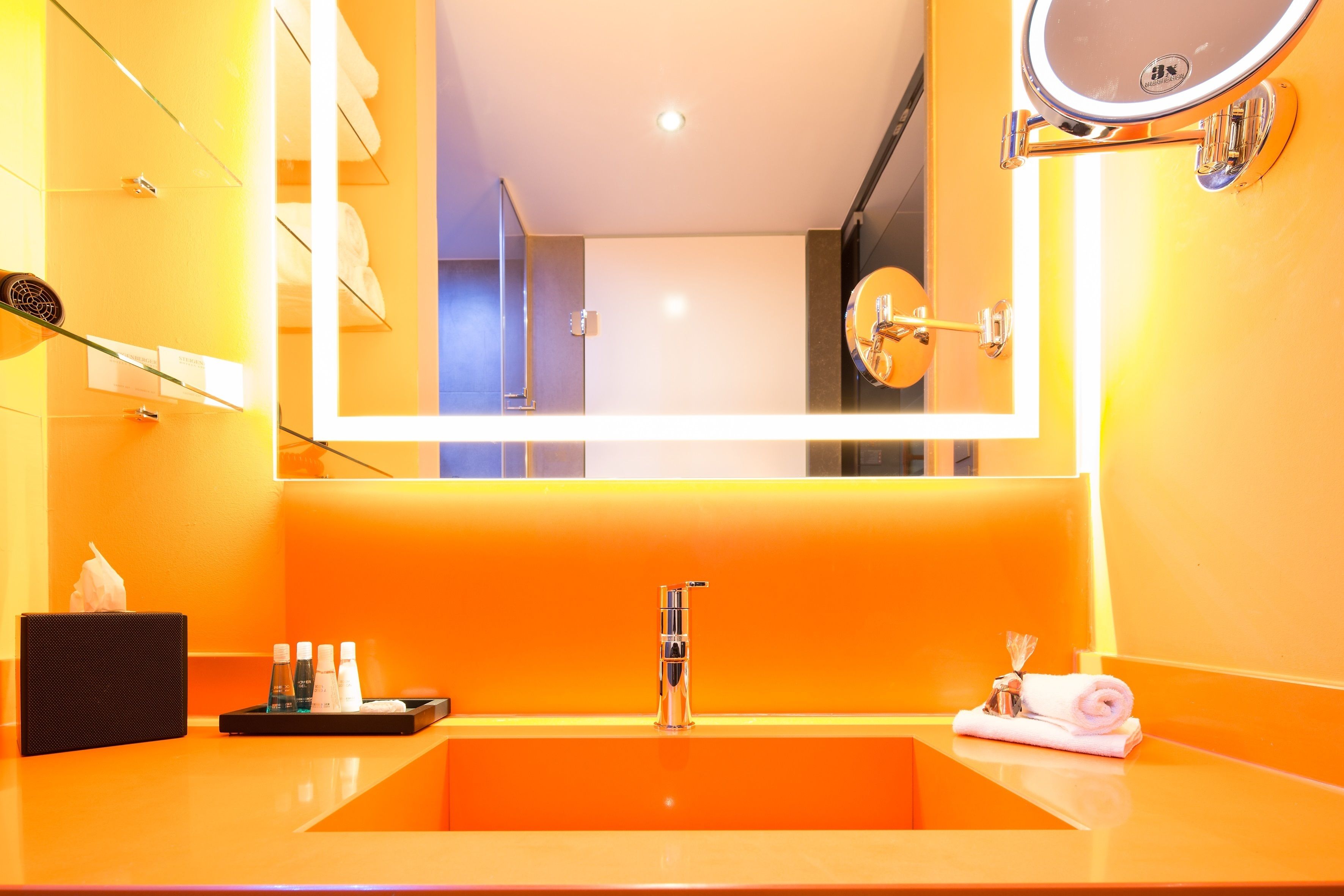 Een badkamer met een grote spiegel, een wastafel en een handdoekhouder.