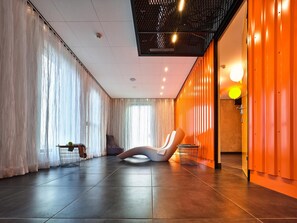 Un interior moderno con un ventanal grande, una silla blanca y una pared con paneles verticales naranja.