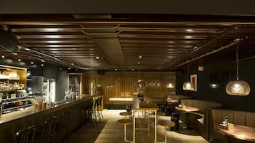 Een moderne bar met een lange toonbank, krukken en hanglampen.